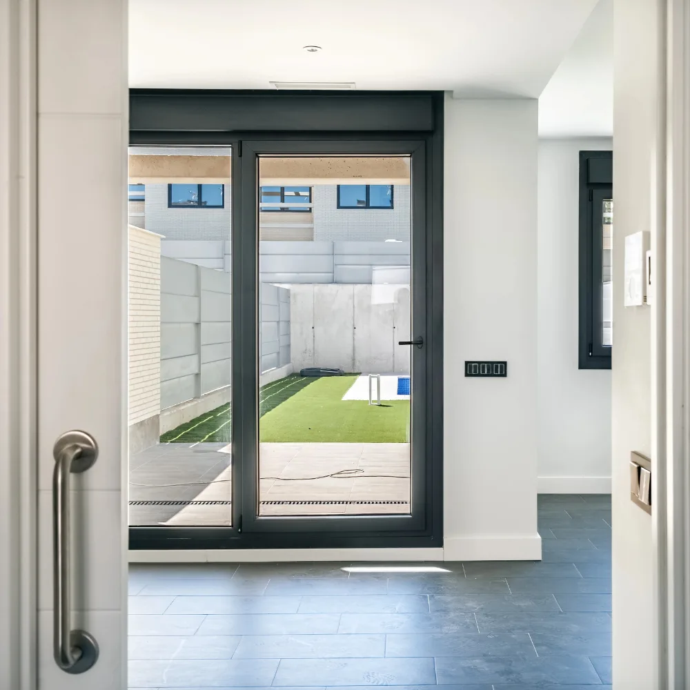Porta finestra scorrevole in legno con vista su giardino e piscina in abitazione residenziale
