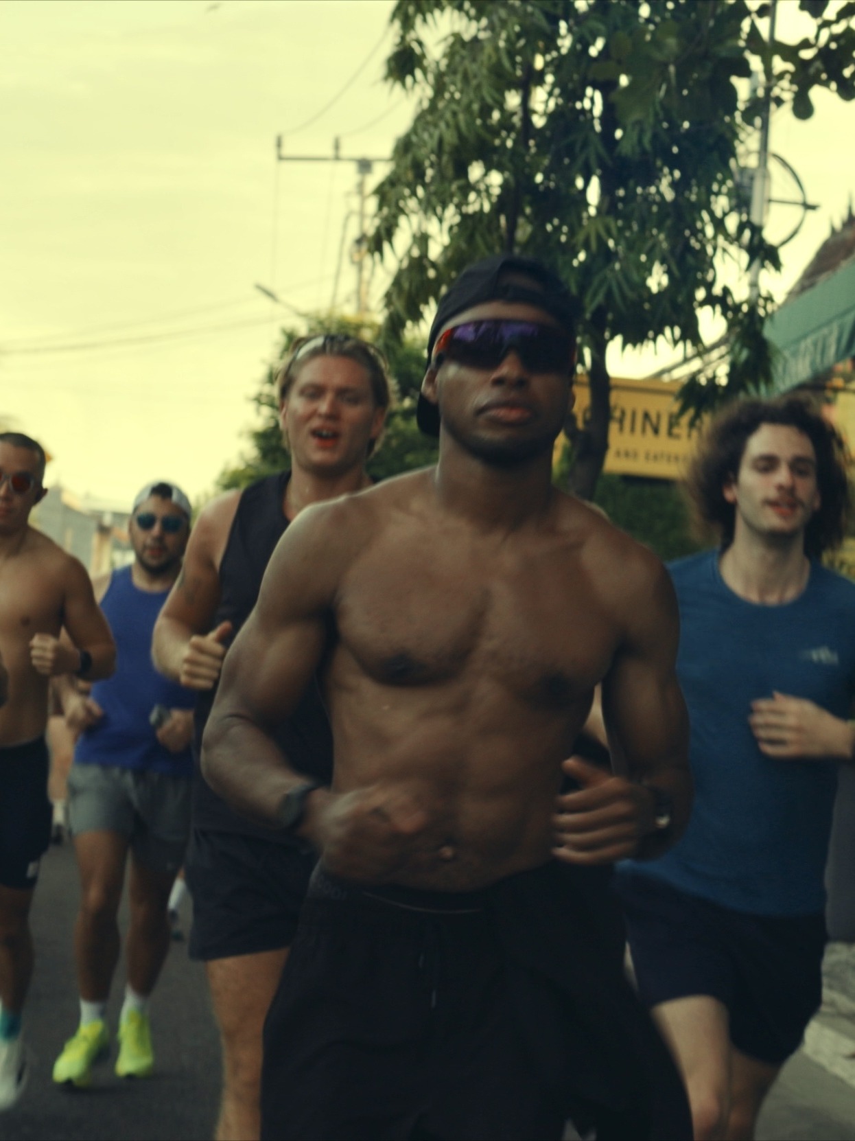 QuHarrison Terry leading a Canggu pack run in Bali, shirtless, black cap backward.