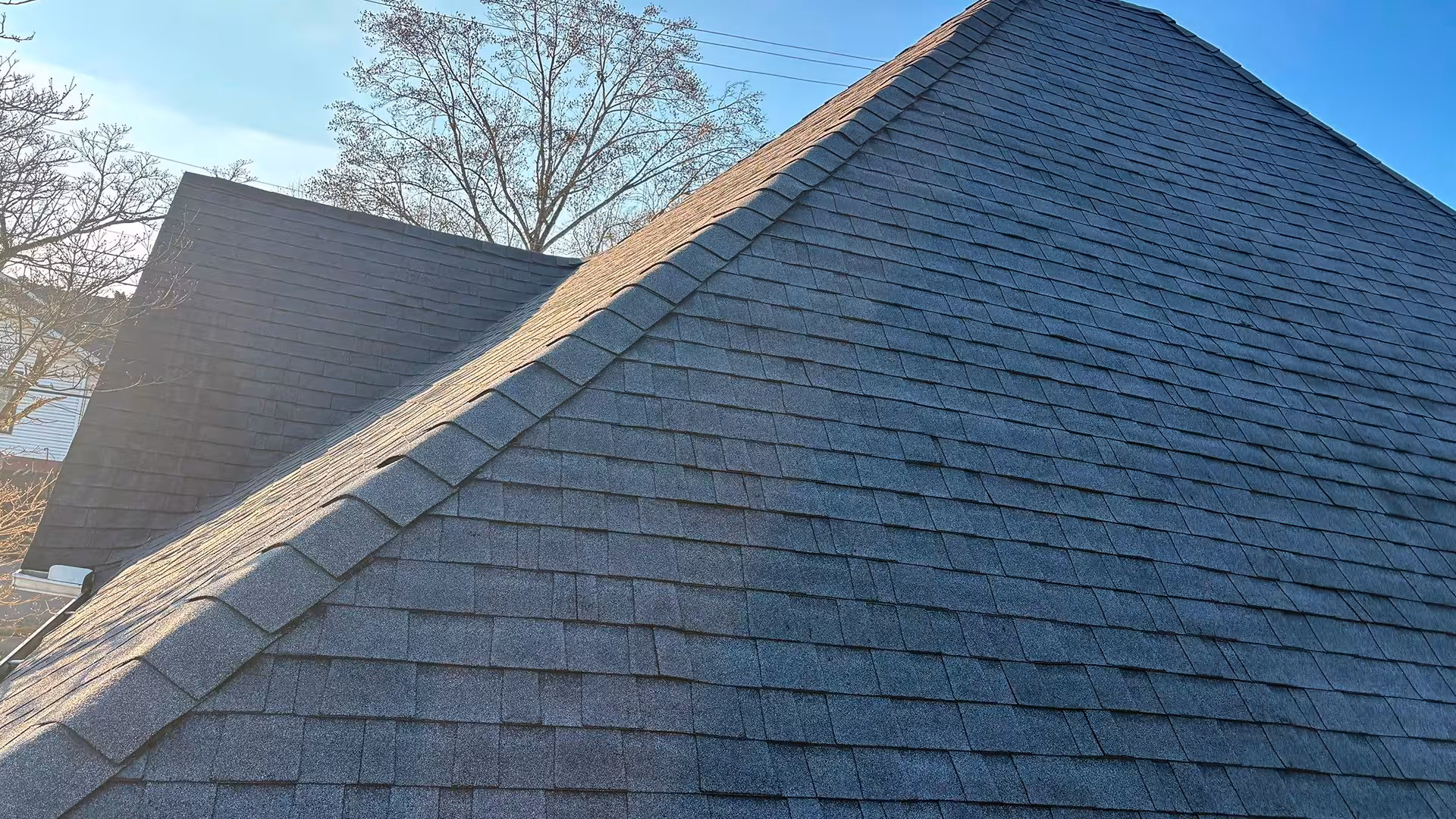 Close-up of roof with lifted and missing shingles exposing the underlayment beneath