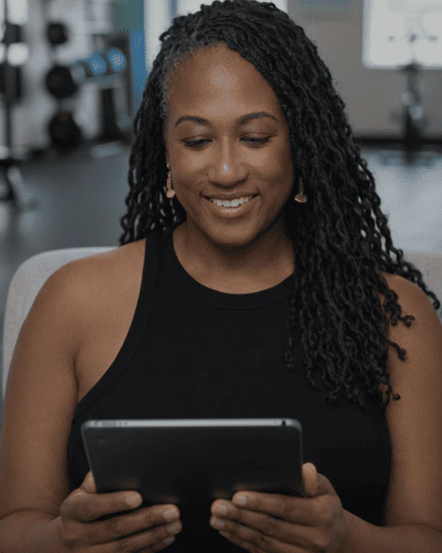 Dianne Adkins-Forte smiling as she reads on a tablet in a fitness studio
