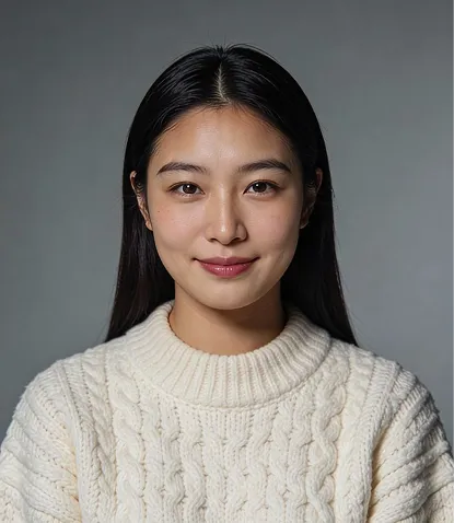 Portrait of a young woman with long black hair wearing a white knitted sweater, smiling gently against a plain gray background.