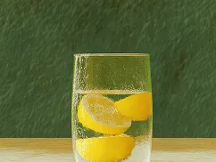 Glass of water with three lemon slices on a wooden surface against a green textured background.