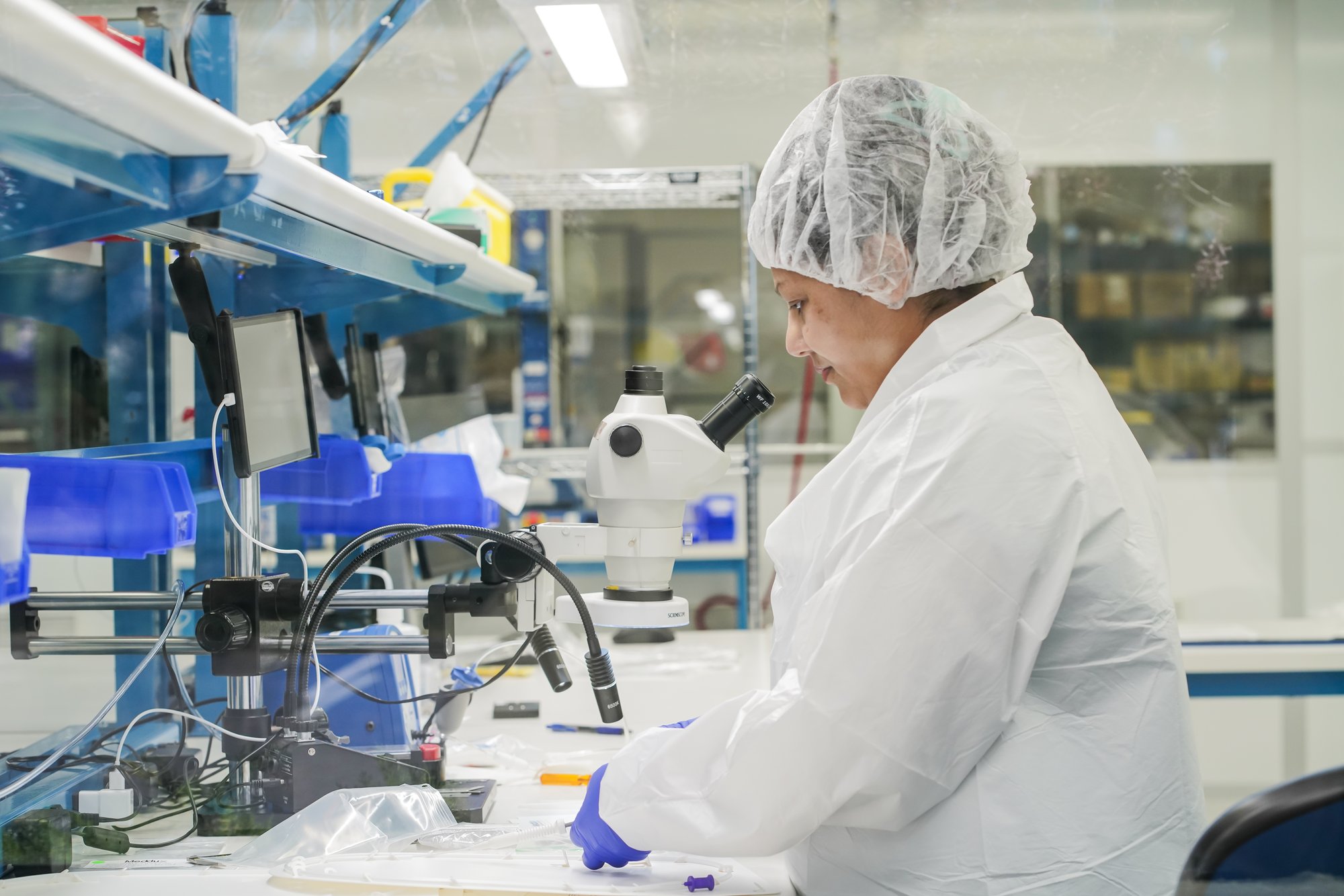 Technician at a process development workstation with microscope