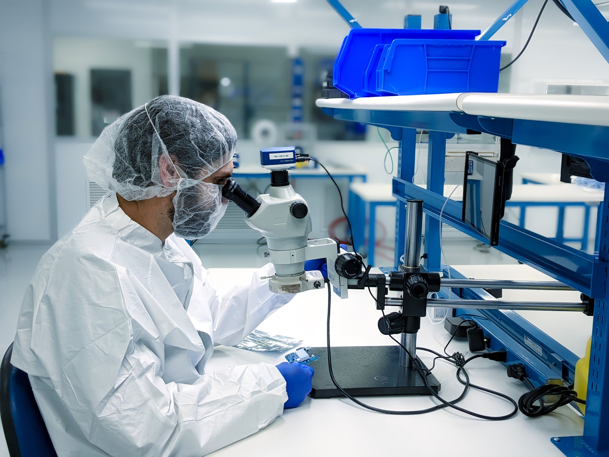 Quality technician inspecting components under a microscope