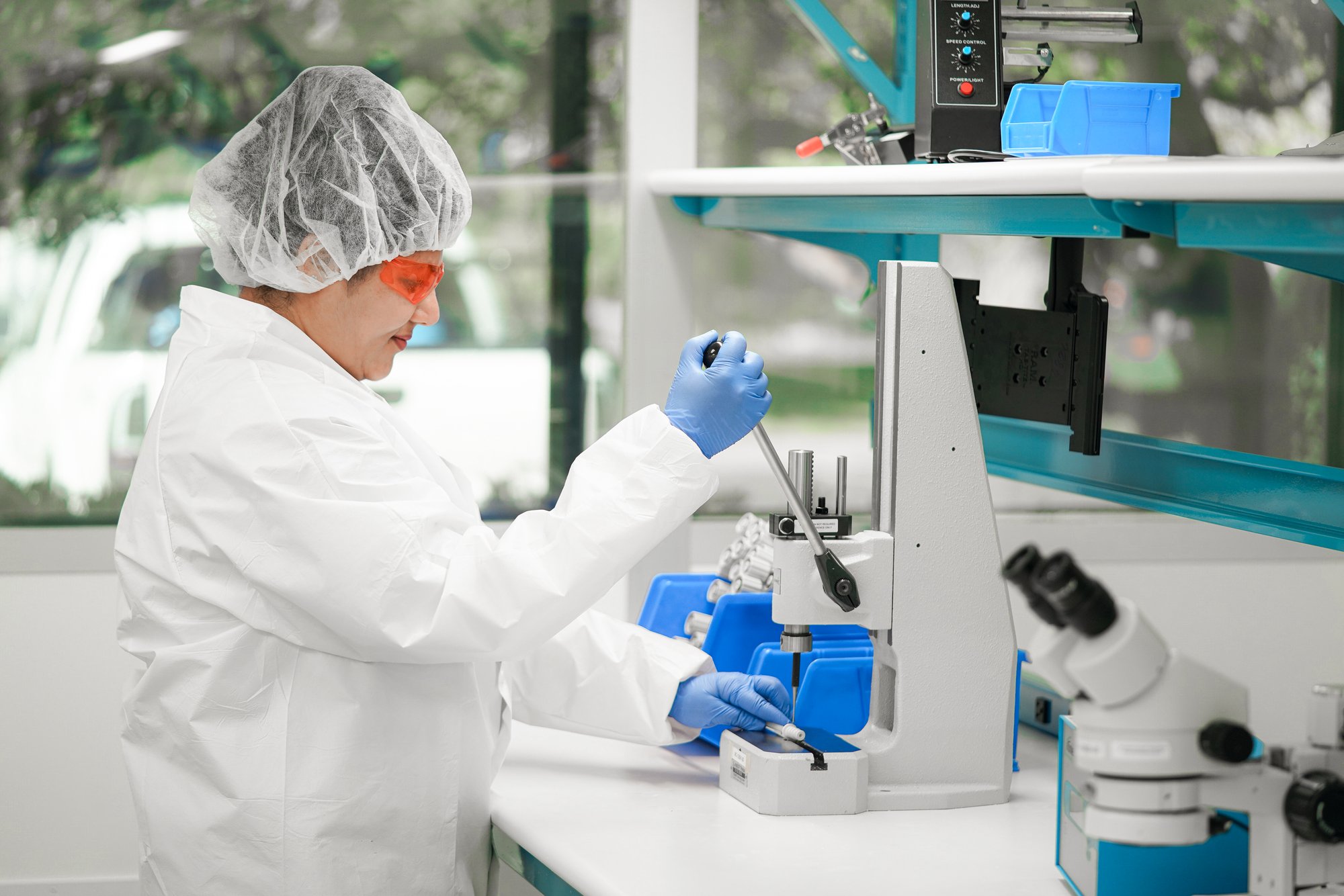 Technician with magnifying headset assembling a catheter device
