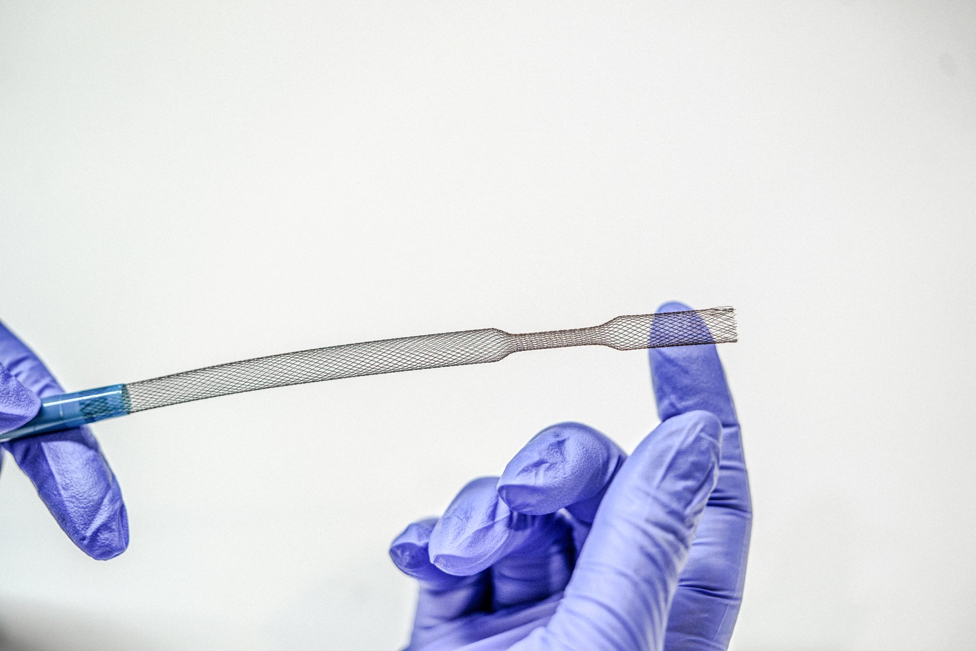 Hands holding a braided mesh catheter section