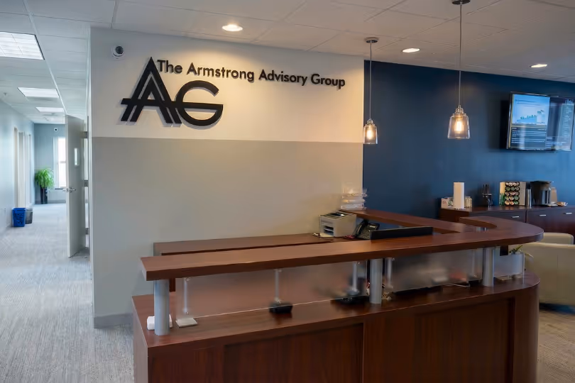 Reception desk area with The Armstrong Advisory Group logo on the wall and a hallway with natural light in the background.