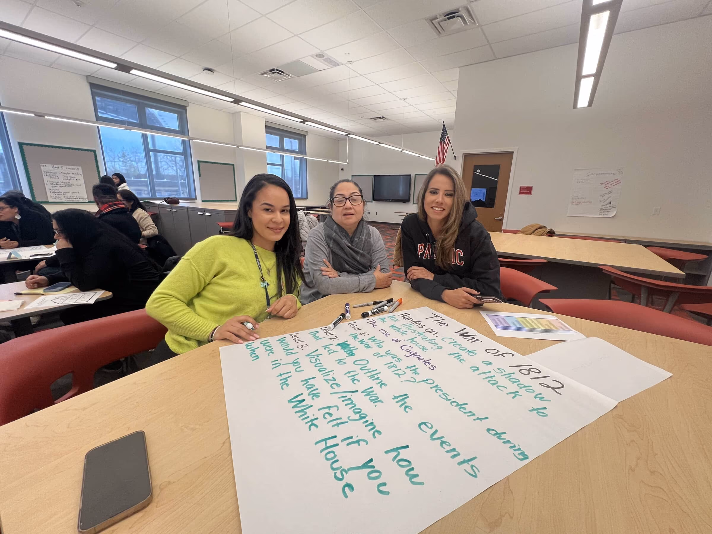 Three educators with a chart paper plan they created in a session