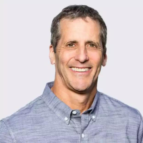 Smiling middle-aged man with short dark hair wearing a light blue button-up shirt.