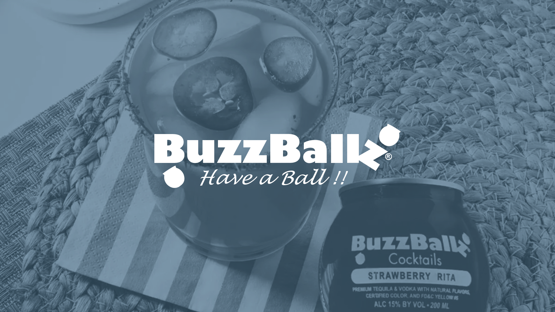 BuzzBallz Strawberry Rita cocktail can and a glass with ice and sliced jalapeños on a mat and striped napkin.