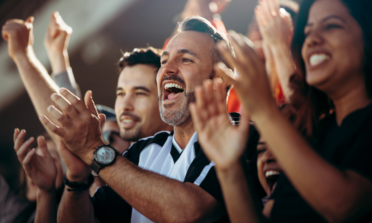 Excited crowd cheering and clapping at a sports game.