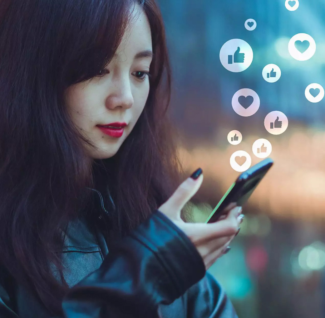 woman holding a phone with emoji icons floating above.