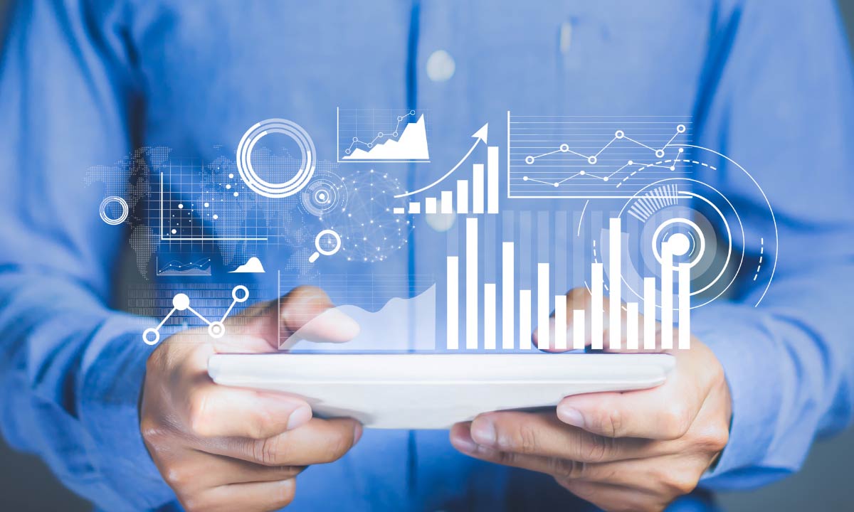 Person holding a tablet with digital business analytics and graphs floating above the screen.