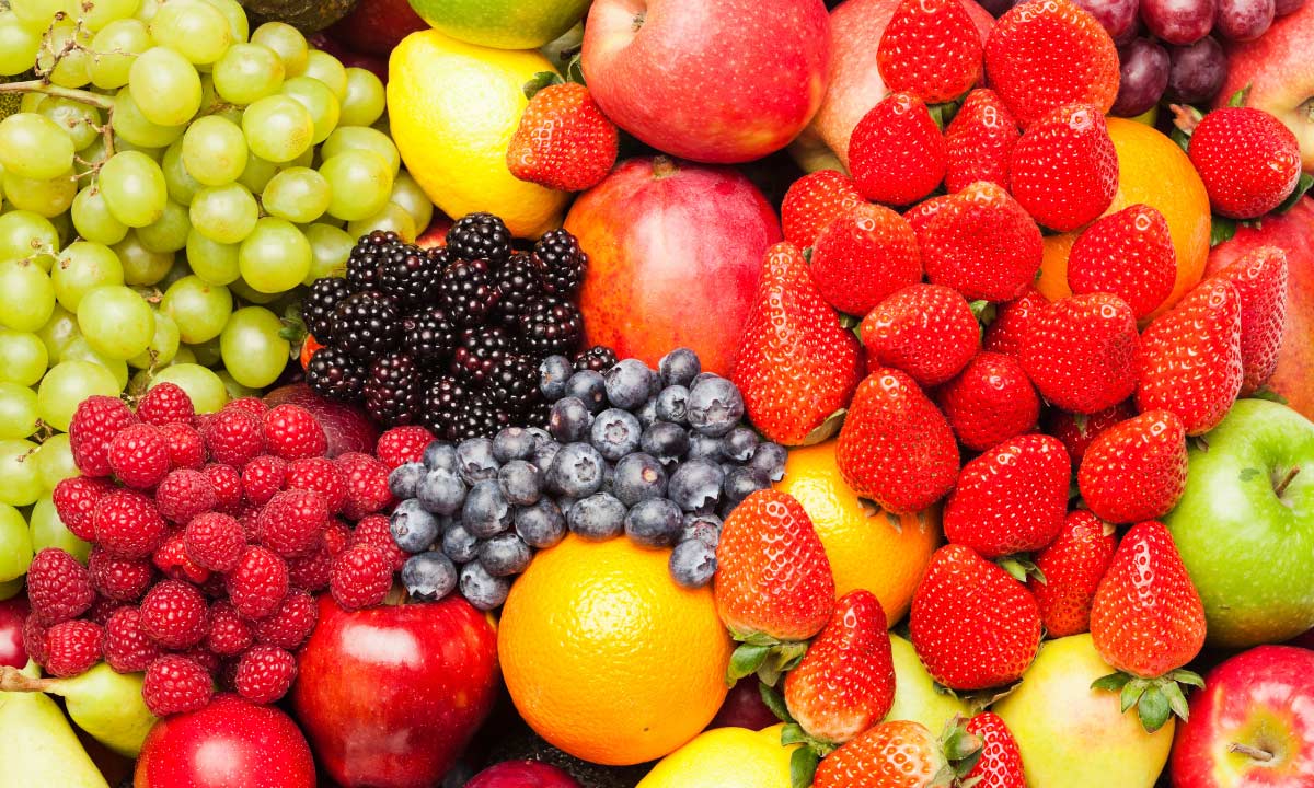 Assortment of fresh fruits including strawberries, blueberries, blackberries, raspberries, green grapes, apples, oranges, lemons, and pears.