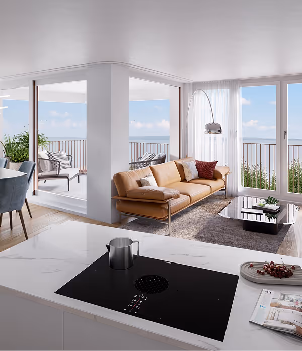 Moderner offener Wohnraum mit braunem Ledersofa, großem Fenster mit Blick auf Balkon und Kücheninsel mit Kochfeld.