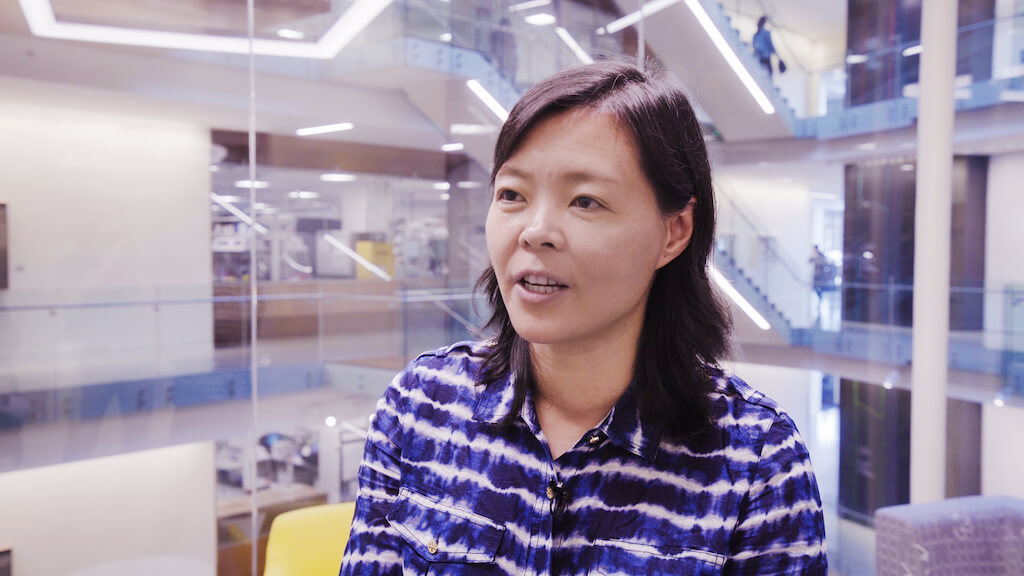 Woman in purple striped shirt smiling in modern office building interior