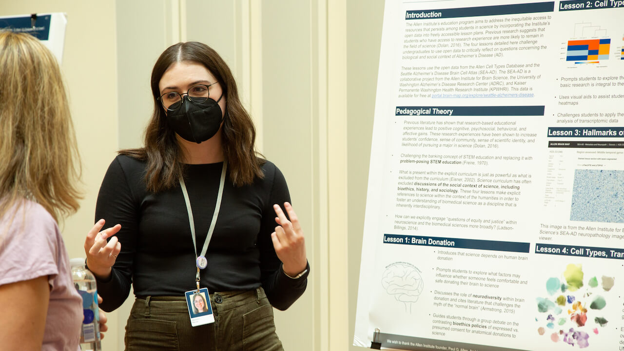 Woman wearing glasses and mask presenting educational neuroscience lesson poster about cell types and brain donation