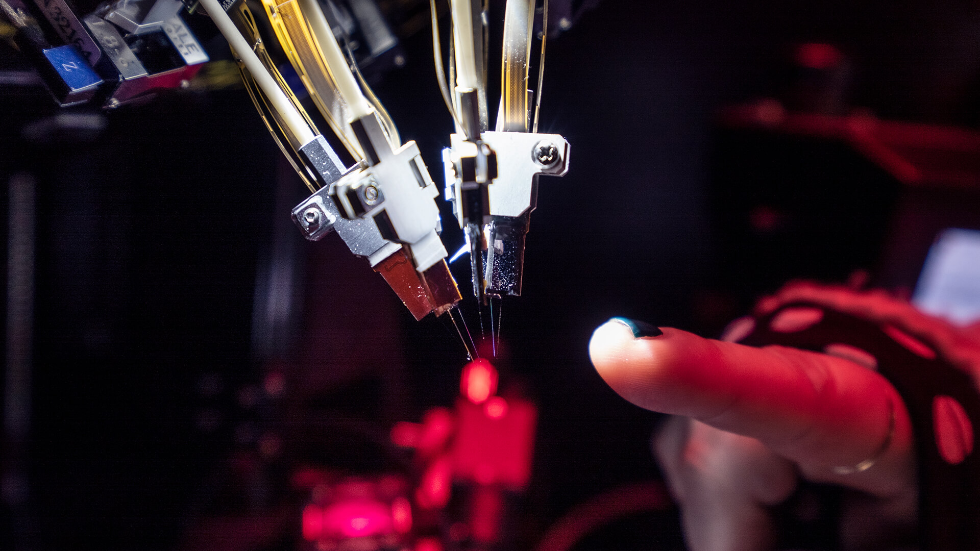 3D printer nozzle with red hot tip extruding filament in dark environment