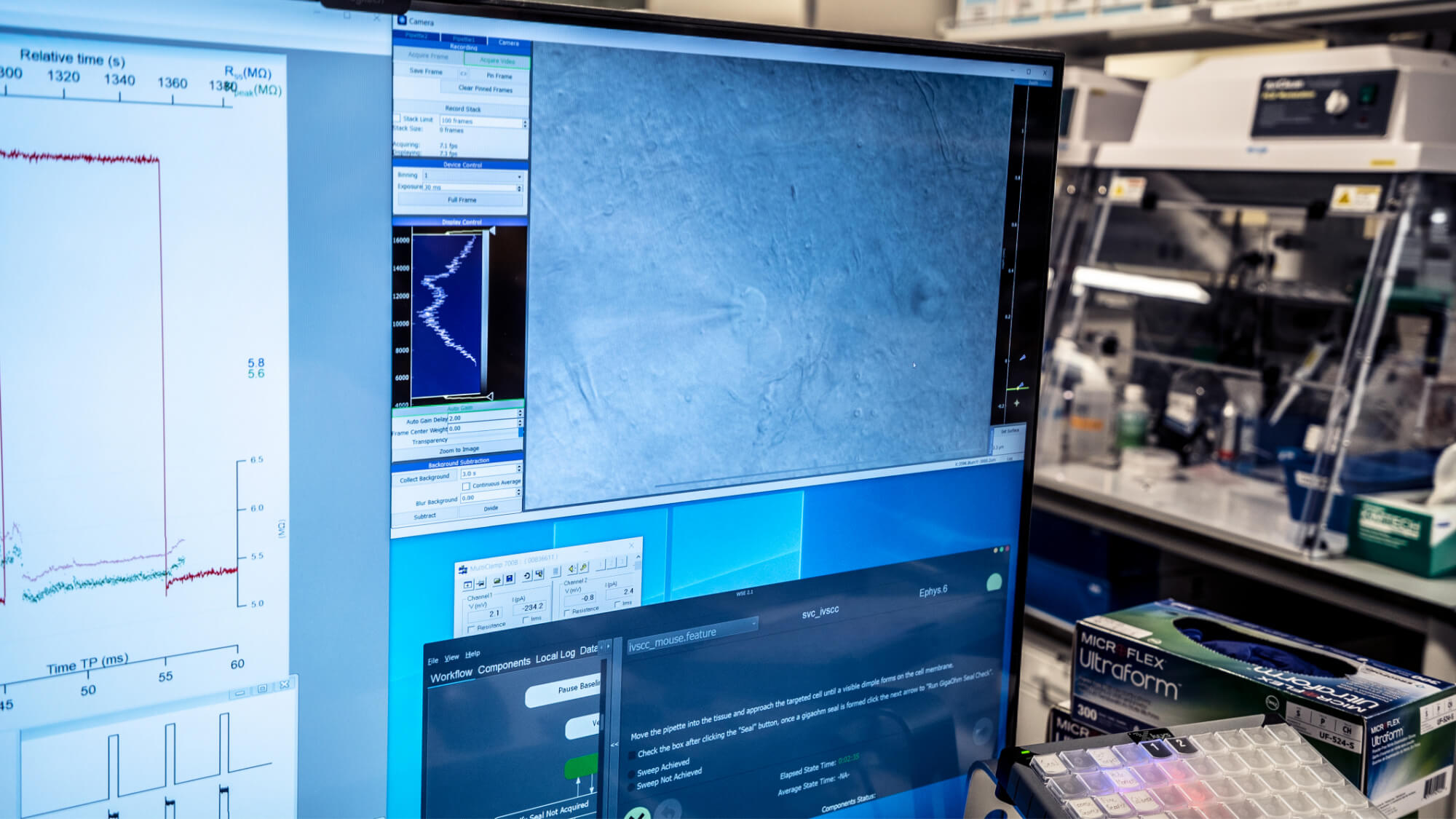 Scientific instruments and computer displays showing data analysis graphs and spectroscopy results in laboratory setting.