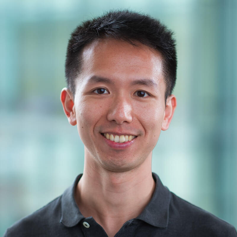 Man smiling at camera wearing dark polo shirt against blurred background