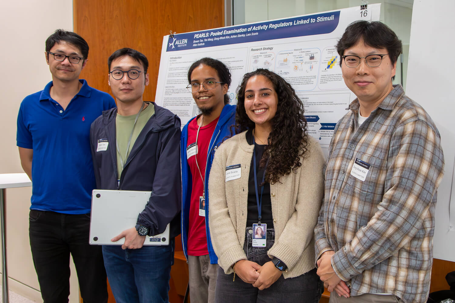 Five researchers posing in front of PEARLS research poster about activity regulators at conference