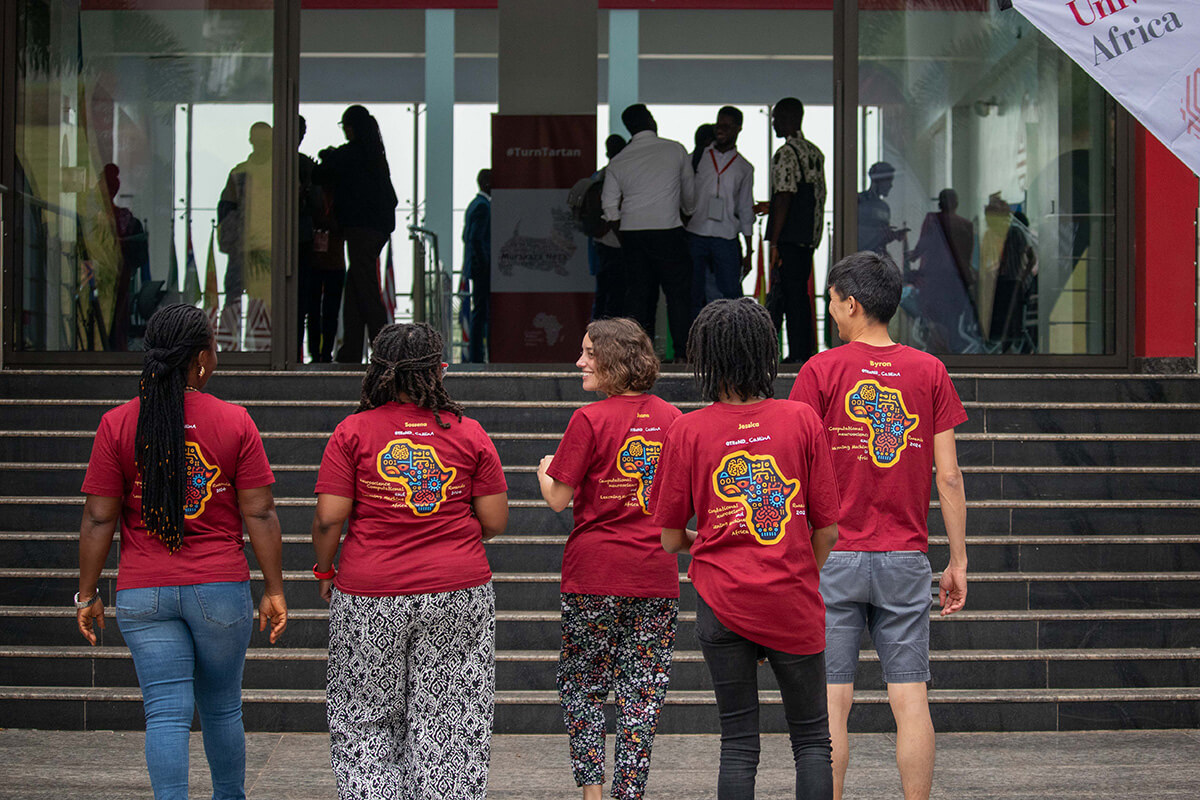Group of five people wearing matching red Africa-themed t-shirts walking up building steps