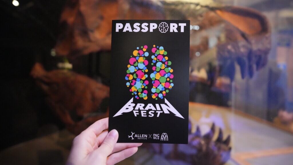 Person holding Brain Fest passport with colorful brain design artwork at event