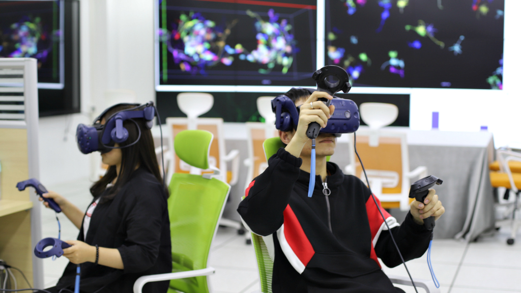 Two people wearing VR headsets and holding controllers in a futuristic virtual reality environment.