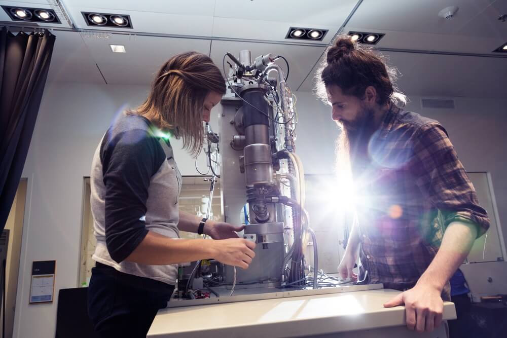 Two scientists working together on a microscopy equipment in a modern research laboratory.