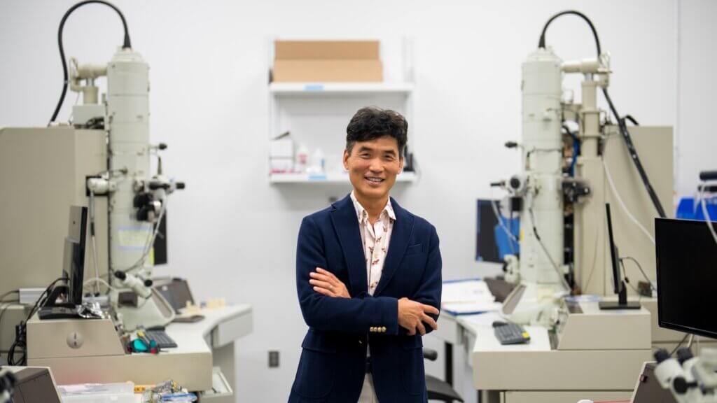 Professional man in lab coat smiling confidently surrounded by scientific equipment