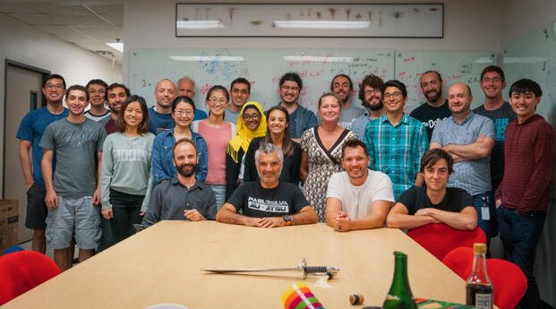 Group of diverse people smiling together in a bright office or classroom setting.