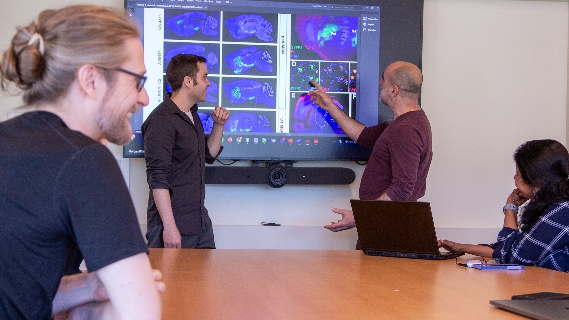 Researchers discuss brain scan images on large laboratory display monitor