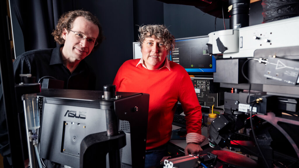 Two technicians working with computer equipment and electronic devices in laboratory setting