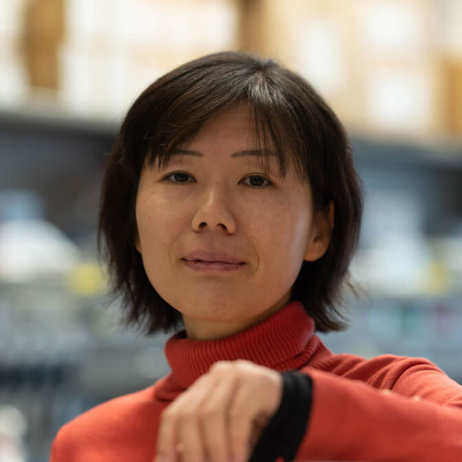 Woman with short black hair wearing red turtleneck sweater indoors