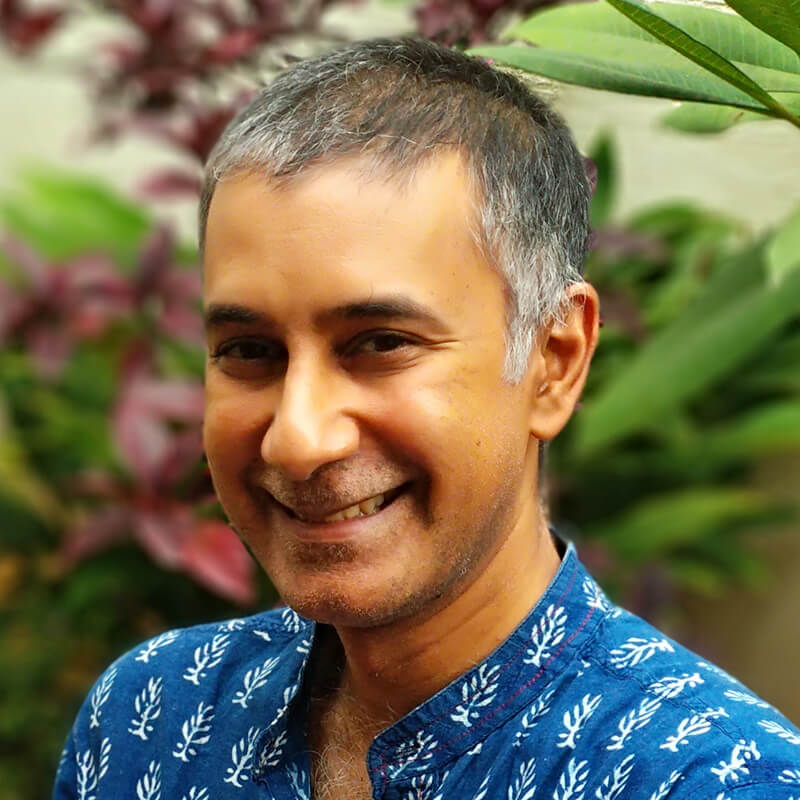 Middle-aged man with gray hair smiling in blue patterned shirt outdoors