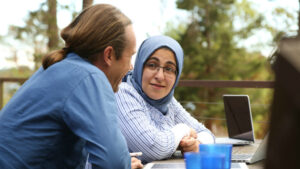 Two women outdoors using laptop and tablet for digital communication or work