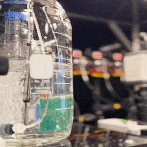 Clear plastic water bottle with green label on electronics workbench with blurred background equipment