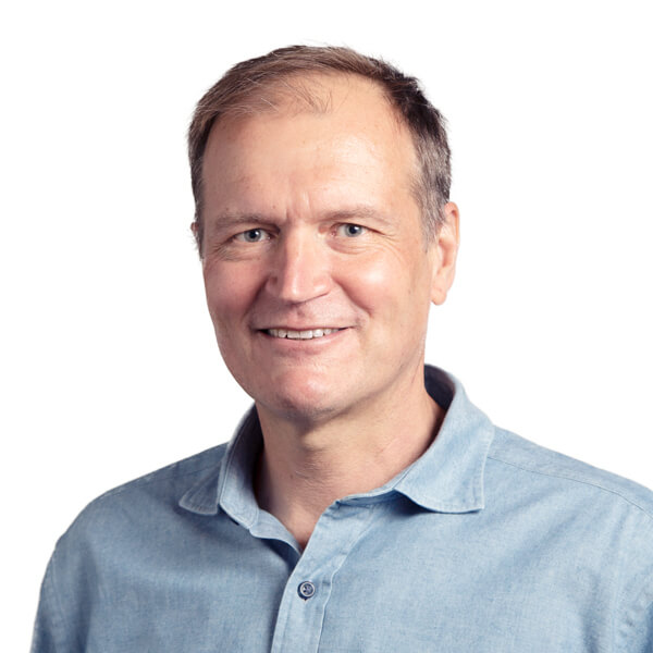 Middle-aged man smiling at camera wearing light blue collared shirt