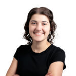 Young person with shoulder-length wavy dark hair wearing a black shirt