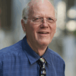 Smiling older man with glasses wearing blue shirt and tie