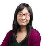 Woman with glasses and long dark hair wearing purple cardigan smiling