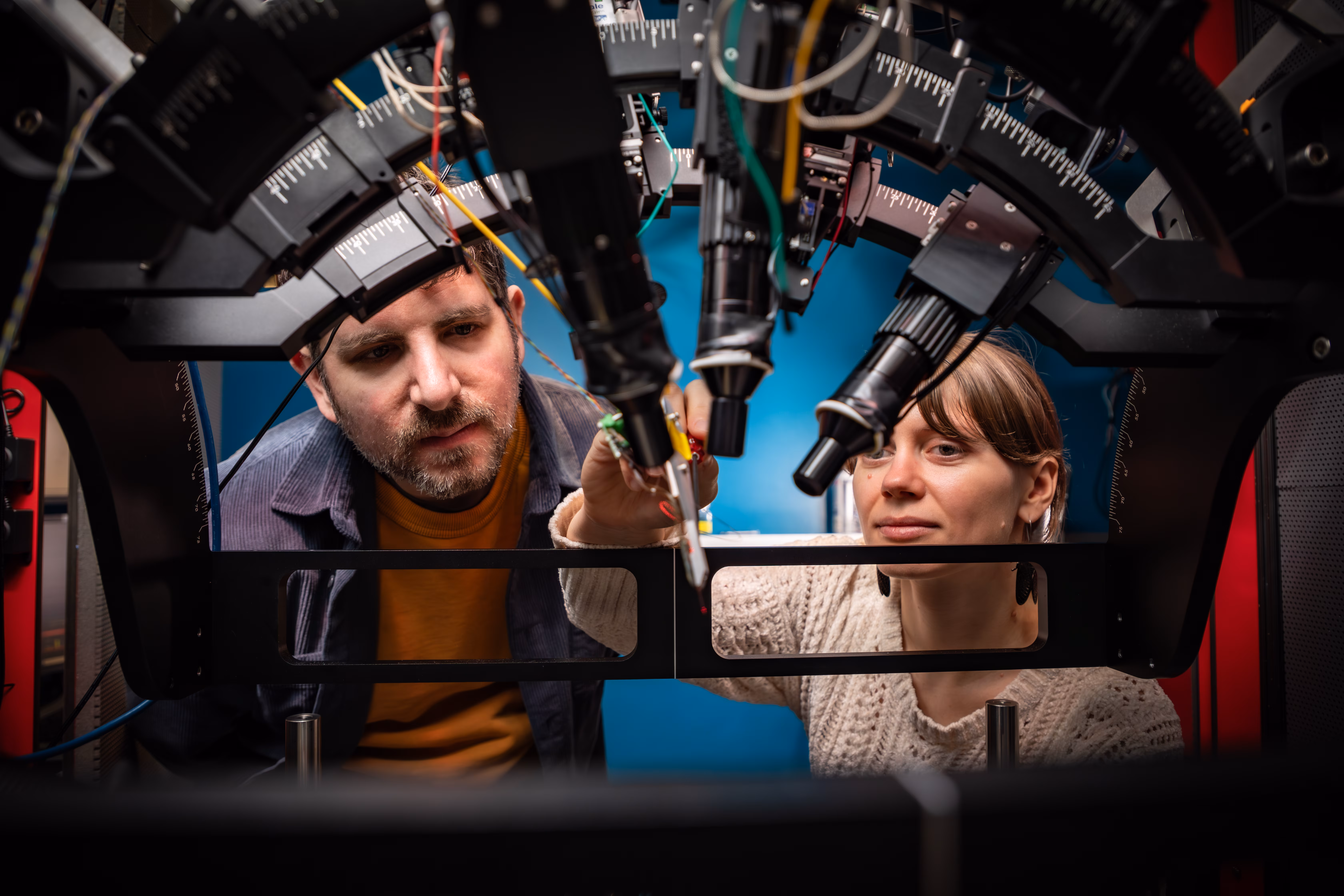 Two people working on professional lighting equipment and electrical components in studio setup