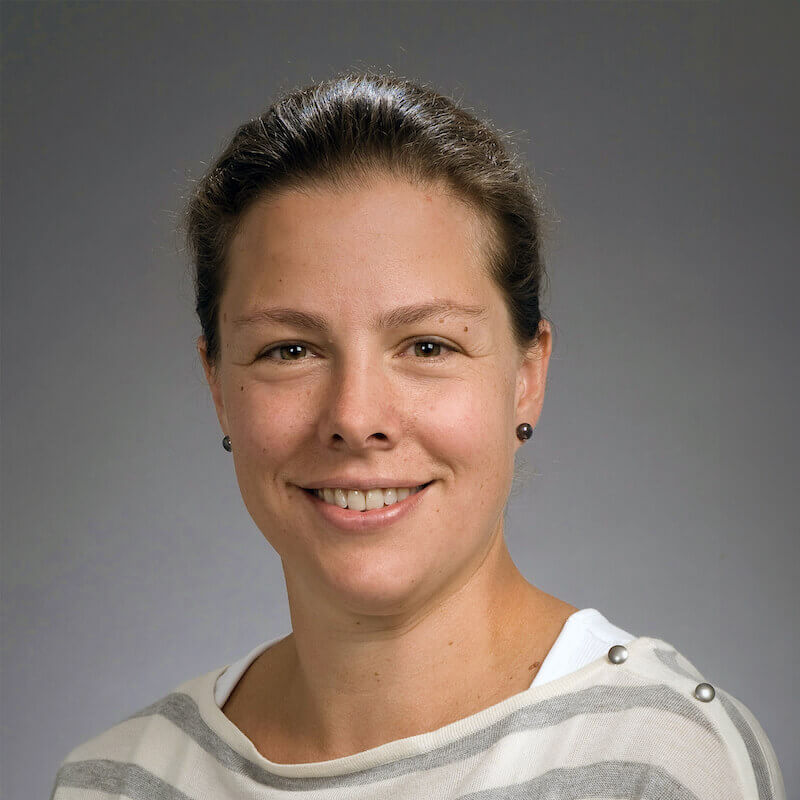 Portrait of a smiling woman with dark hair wearing a striped shirt