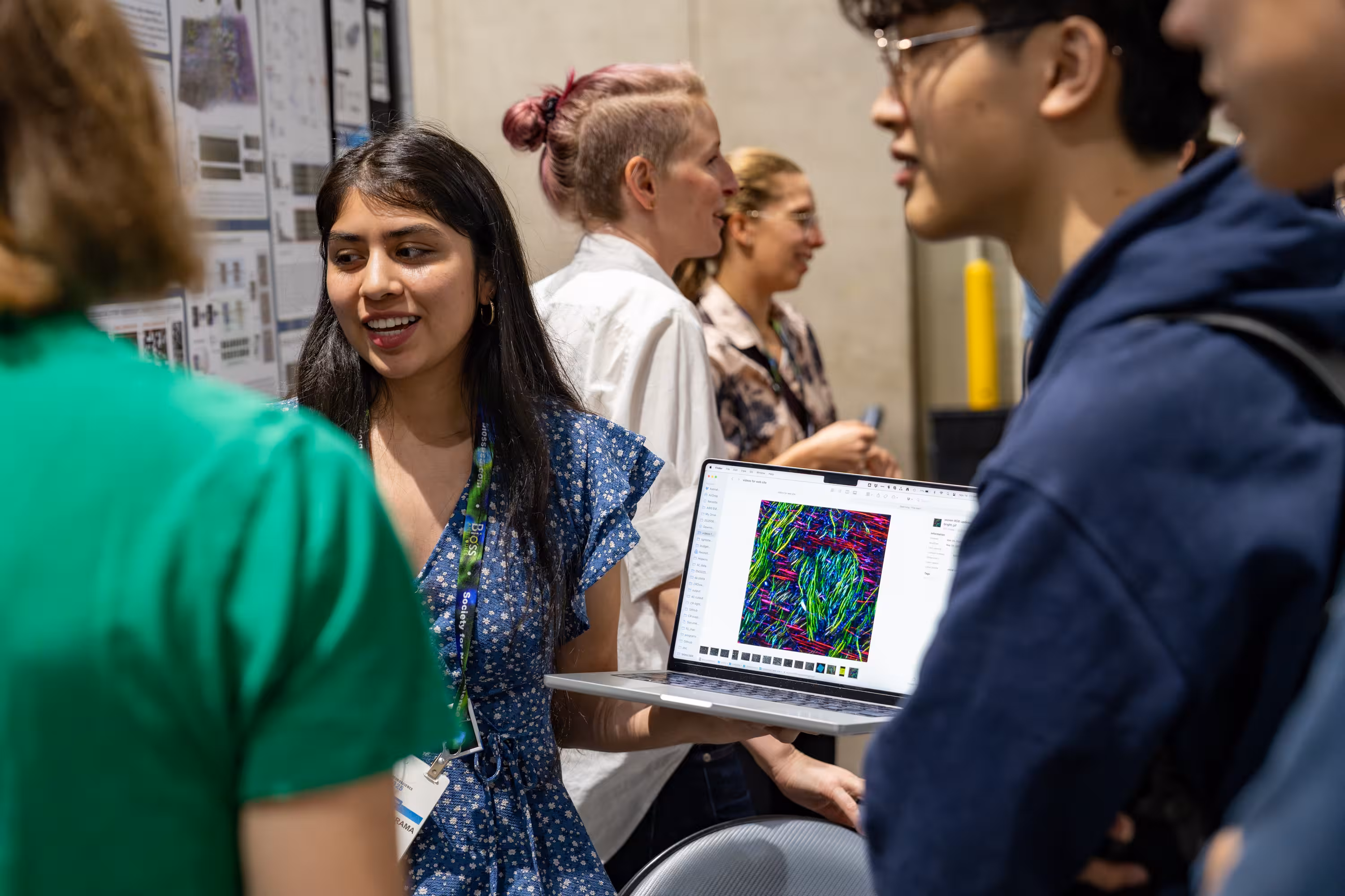 Scientists present colorful microscopy research data on laptop at academic conference poster session