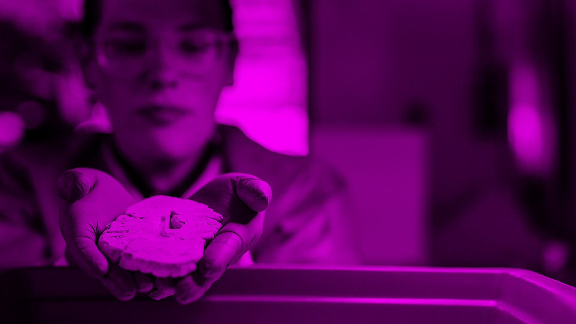 Child holding heart-shaped cookie with magenta neon lighting in blurred background