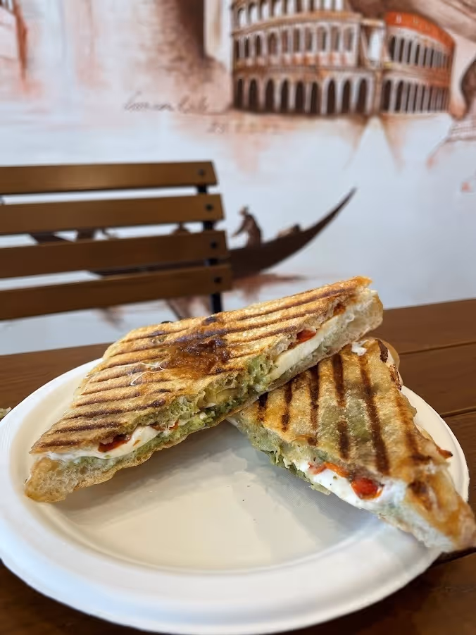 A plate holds a sandwich beside a steaming cup of coffee, creating a cozy meal setting.