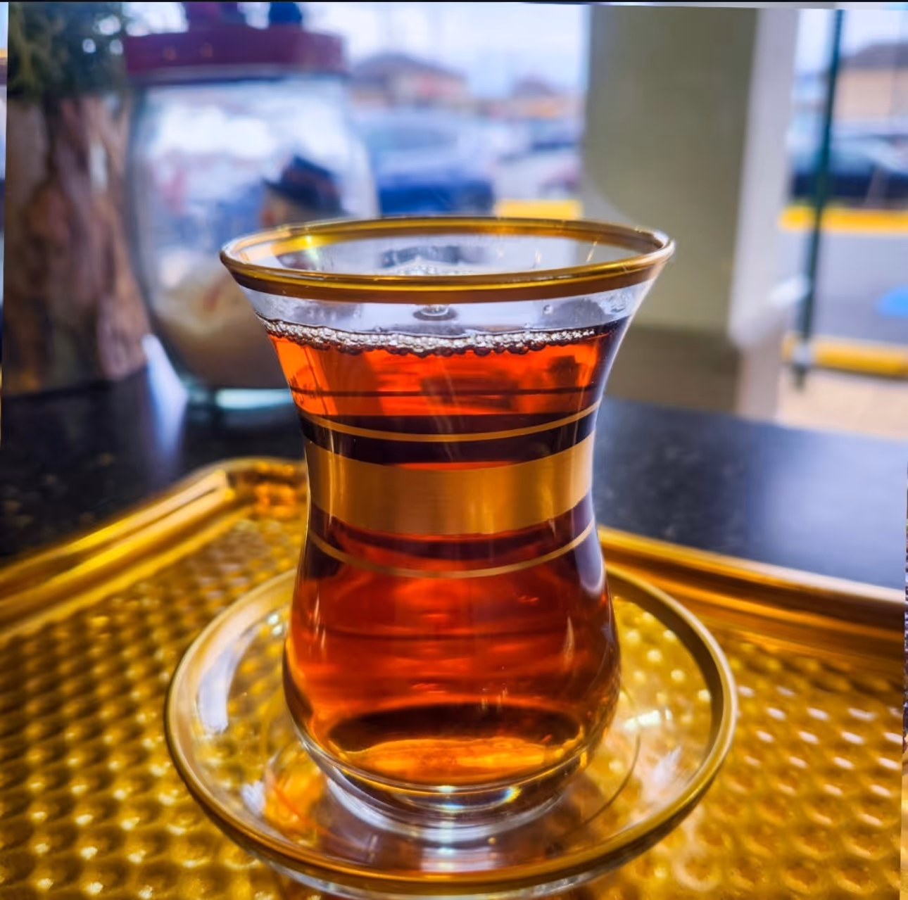 A glass of tea placed elegantly on a gold tray, showcasing a warm beverage in a refined setting.