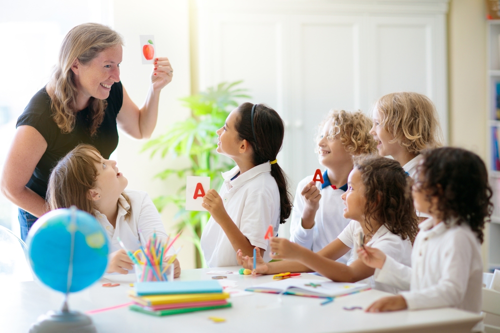 A teacher illustrates why phonics is important by using a flashcard during a lesson with attentive children