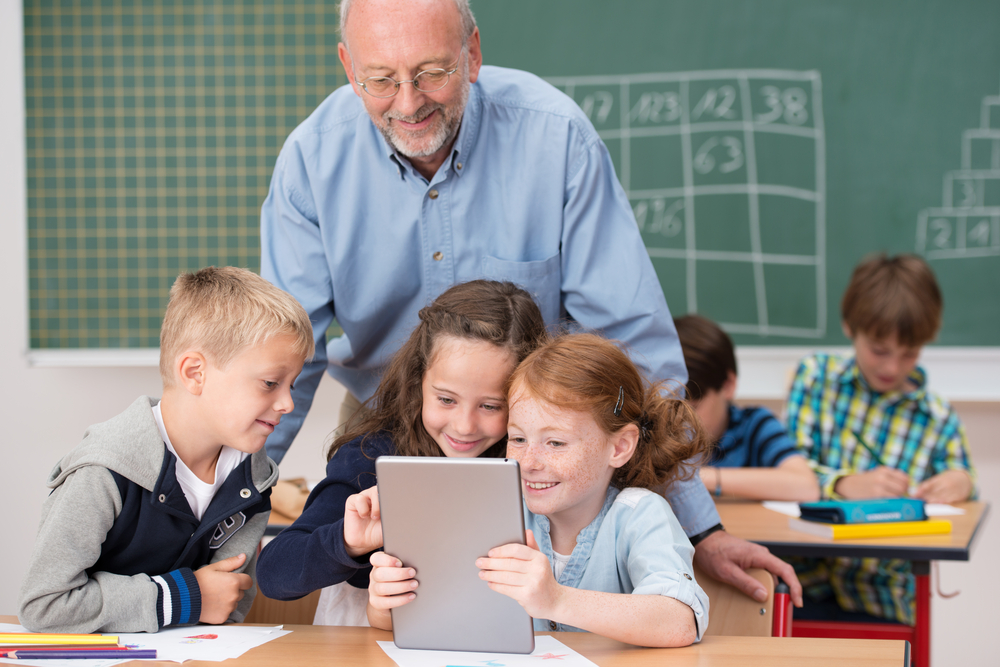 Teacher using a tablet as an interactive reading intervention strategy with students