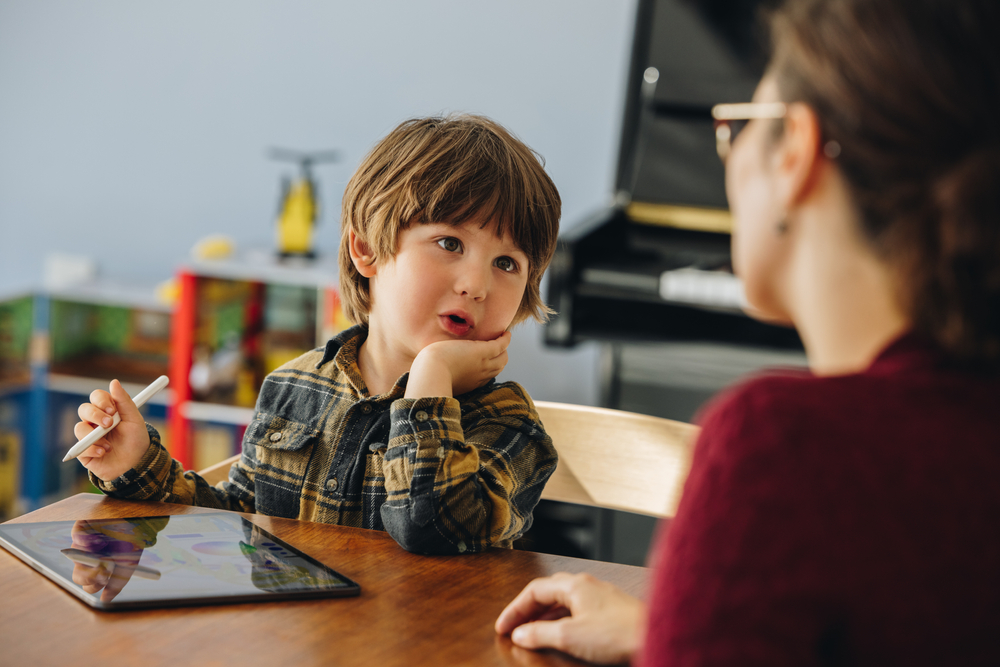 Boy with autism using an educational app on a tablet with adult assistance